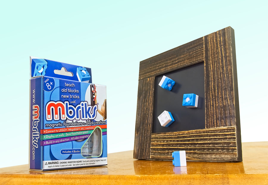 4 MBRIKS magnetic construction blocks positioned on a rustic picture frame (MDisplay) next to an MBRIKS retail box.